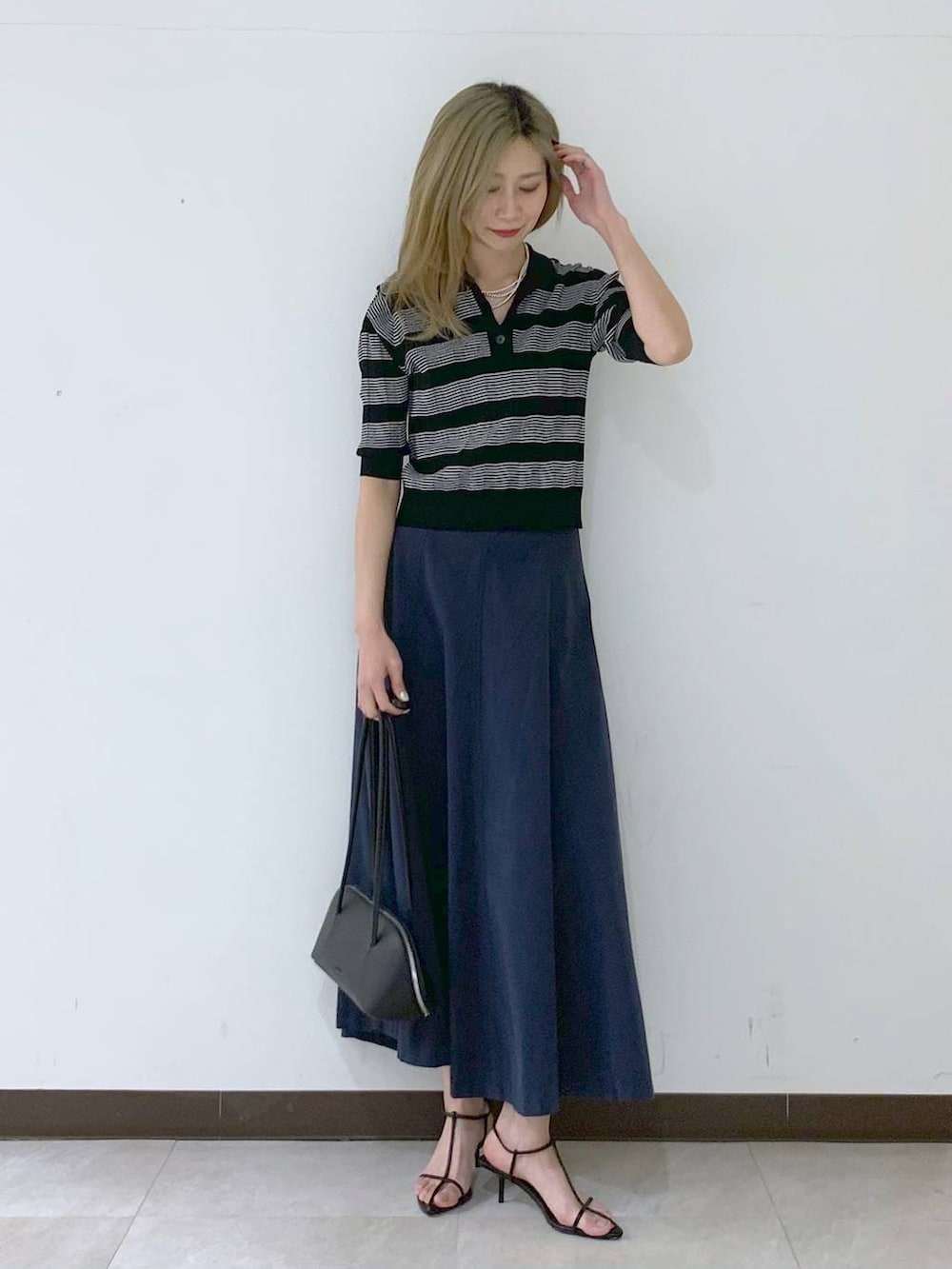 ブラック系のサンダル、ブラック系のハンドバッグ、ブラック系のポロシャツを着用したレディースの春コーディネートの6枚目の写真