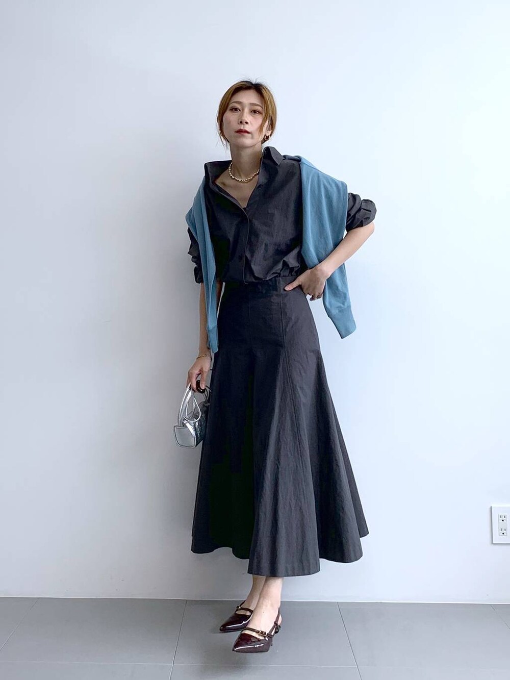 ブルー系のTシャツ/カットソー、シルバー系のショルダーバッグ、グレー系のスカートを着用したレディースの秋コーディネートの2枚目の写真