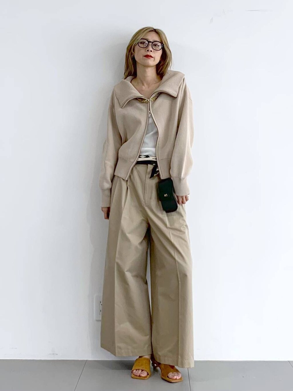 ベージュ系のチノパンツ、ベージュ系のスウェット、ブラウン系のネックレスを着用したレディースの冬コーディネートの2枚目の写真