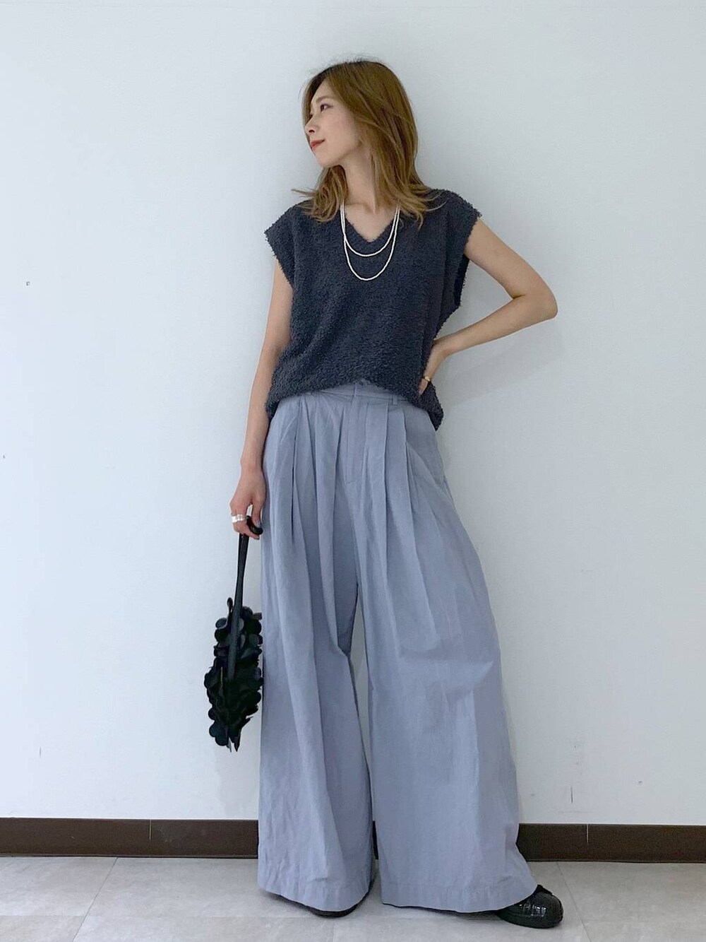 グレー系のニット/セーター、ブラック系のショルダーバッグ、ブラック系のスニーカーを着用したレディースの夏コーディネートの4枚目の写真