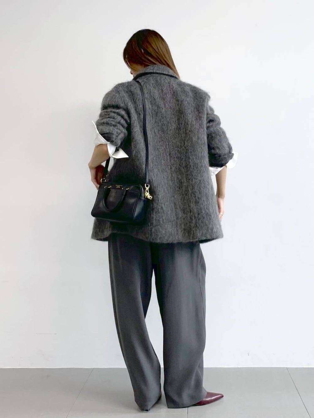 グレー系のその他パンツ、レッド系のブーツ、ブラック系のボストンバッグを着用したレディースの冬コーディネートの3枚目の写真