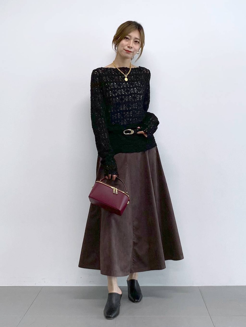 ブラック系のTシャツ/カットソー、ブラウン系のスカート、レッド系のハンドバッグを着用したレディースの冬コーディネートの6枚目の写真