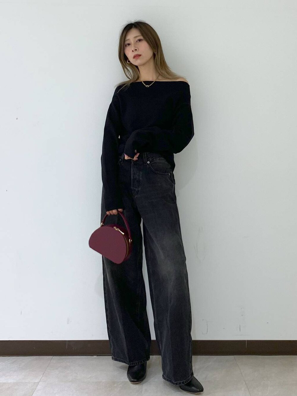 ブラック系のニット/セーター、ブラック系のデニムパンツ、レッド系のハンドバッグを着用したレディースの秋コーディネートの7枚目の写真