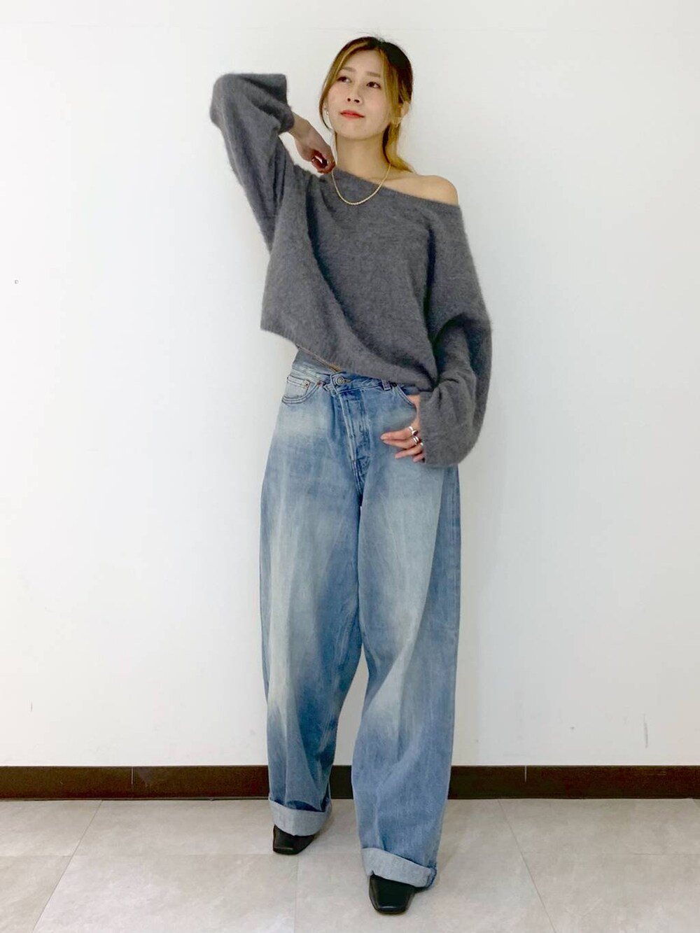 グレー系のニット/セーター、ブルー系のデニムパンツ、ゴールド系のネックレスを着用したレディースの冬コーディネートの6枚目の写真