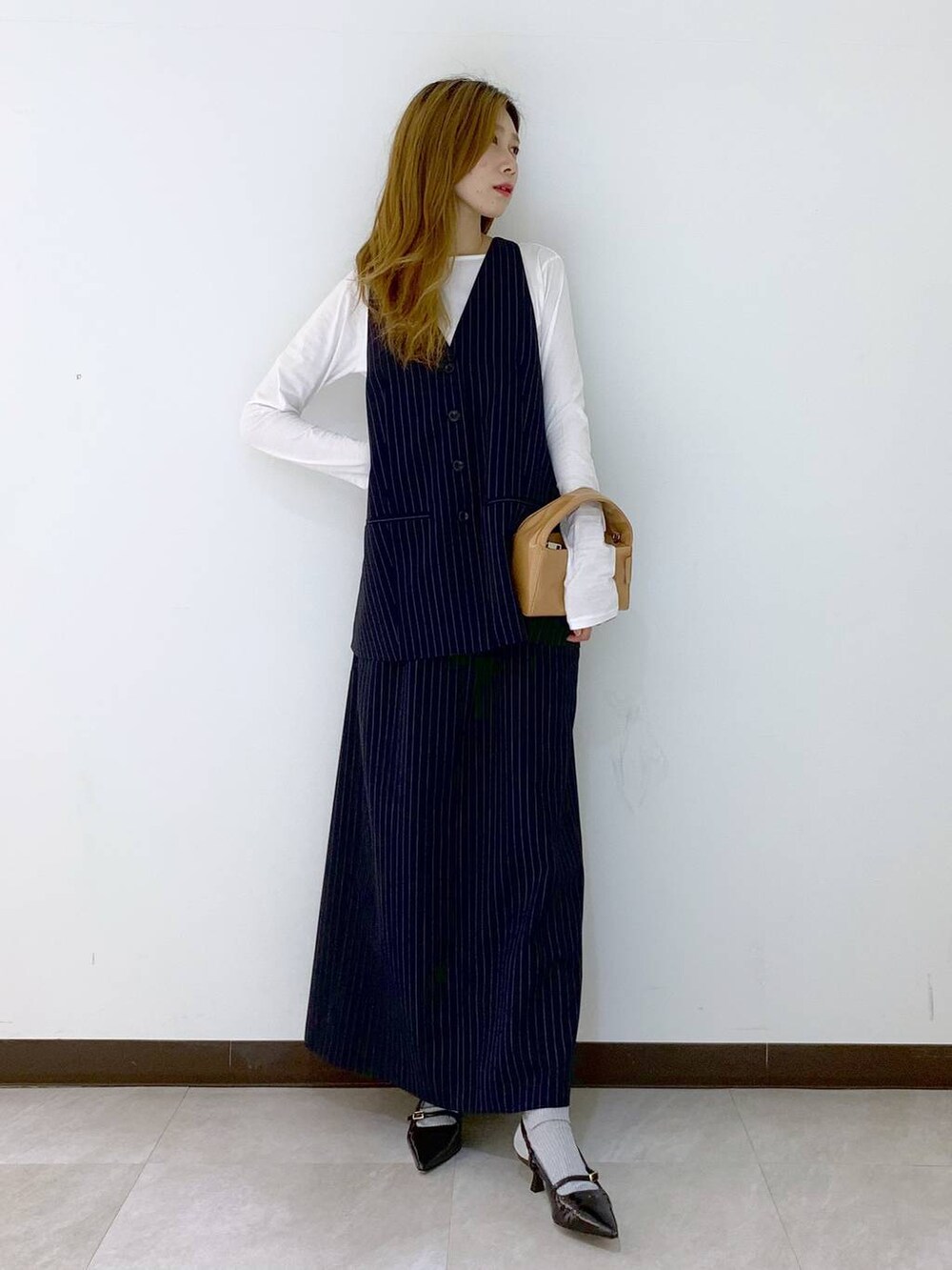 ブルー系のベスト、ブルー系のスカート、ホワイト系のTシャツ/カットソーを着用したレディースの秋コーディネートの5枚目の写真