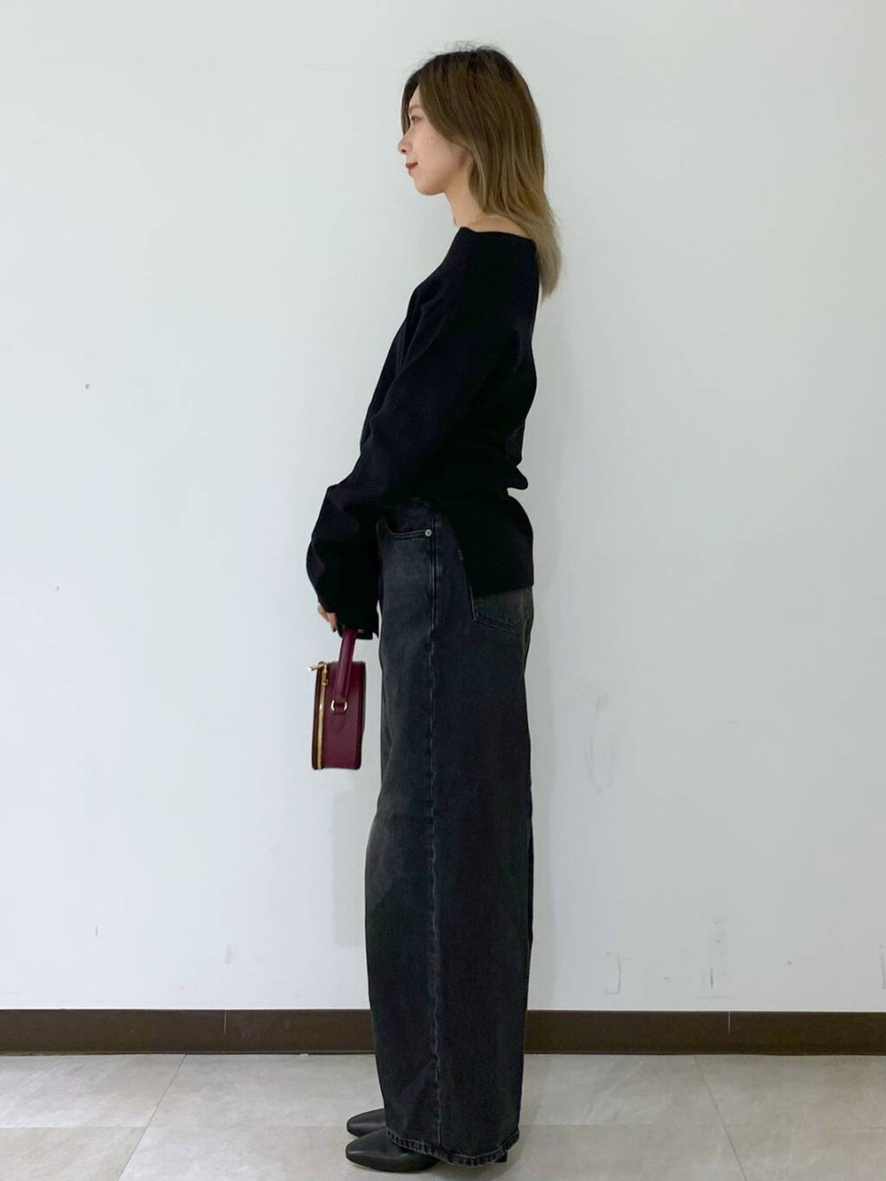 ブラック系のニット/セーター、ブラック系のデニムパンツ、レッド系のハンドバッグを着用したレディースの秋コーディネートの3枚目の写真
