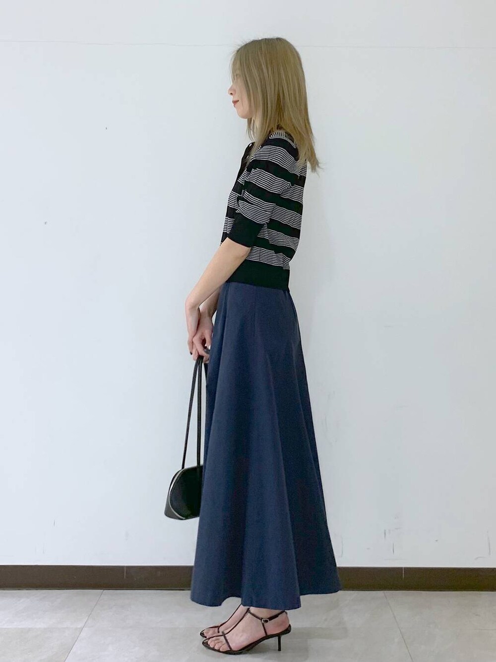 ブラック系のサンダル、ブラック系のハンドバッグ、ブラック系のポロシャツを着用したレディースの春コーディネートの3枚目の写真