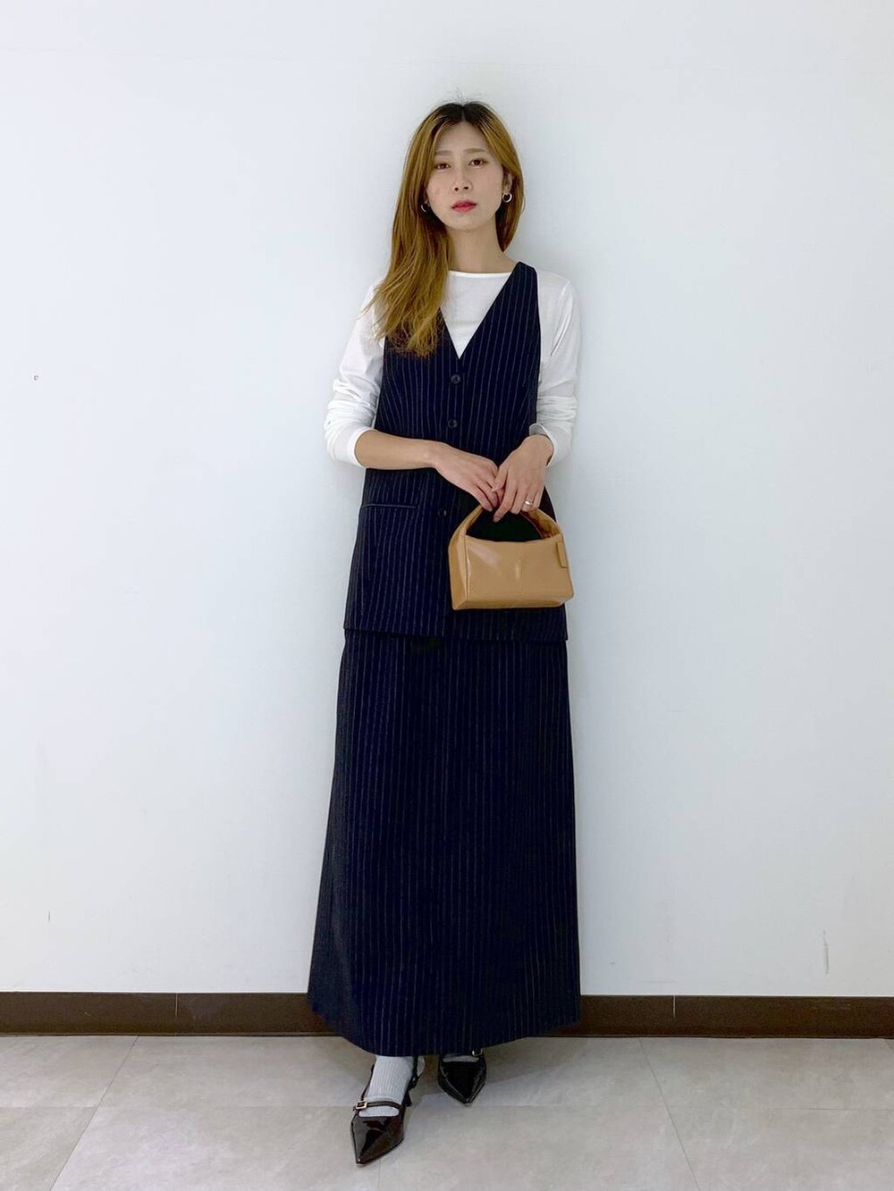 ブルー系のベスト、ブルー系のスカート、ホワイト系のTシャツ/カットソーを着用したレディースの秋コーディネートの2枚目の写真