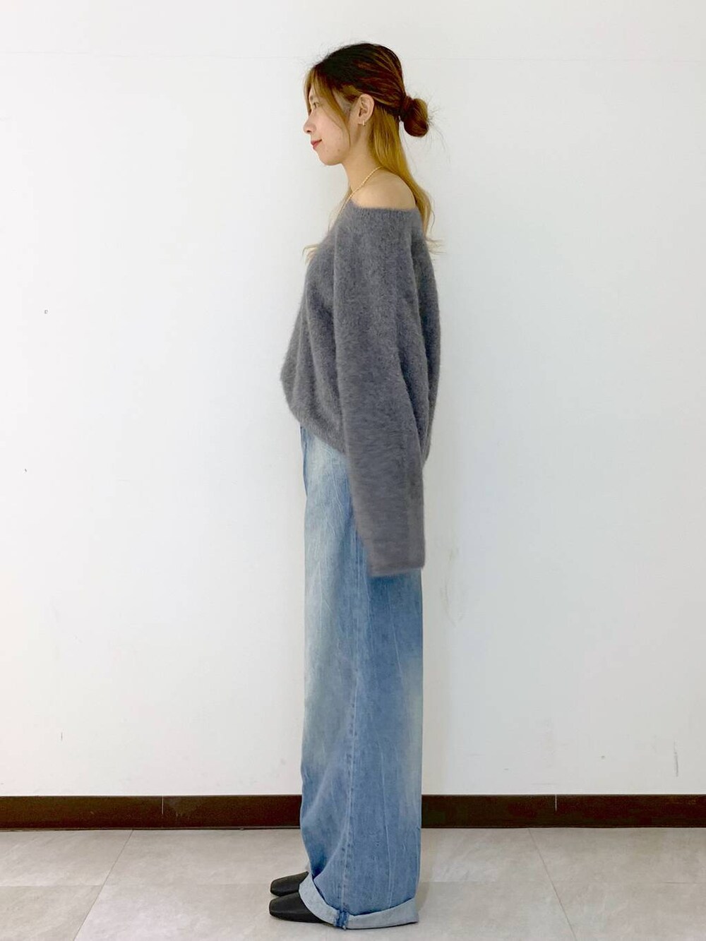 グレー系のニット/セーター、ブルー系のデニムパンツ、ゴールド系のネックレスを着用したレディースの冬コーディネートの3枚目の写真
