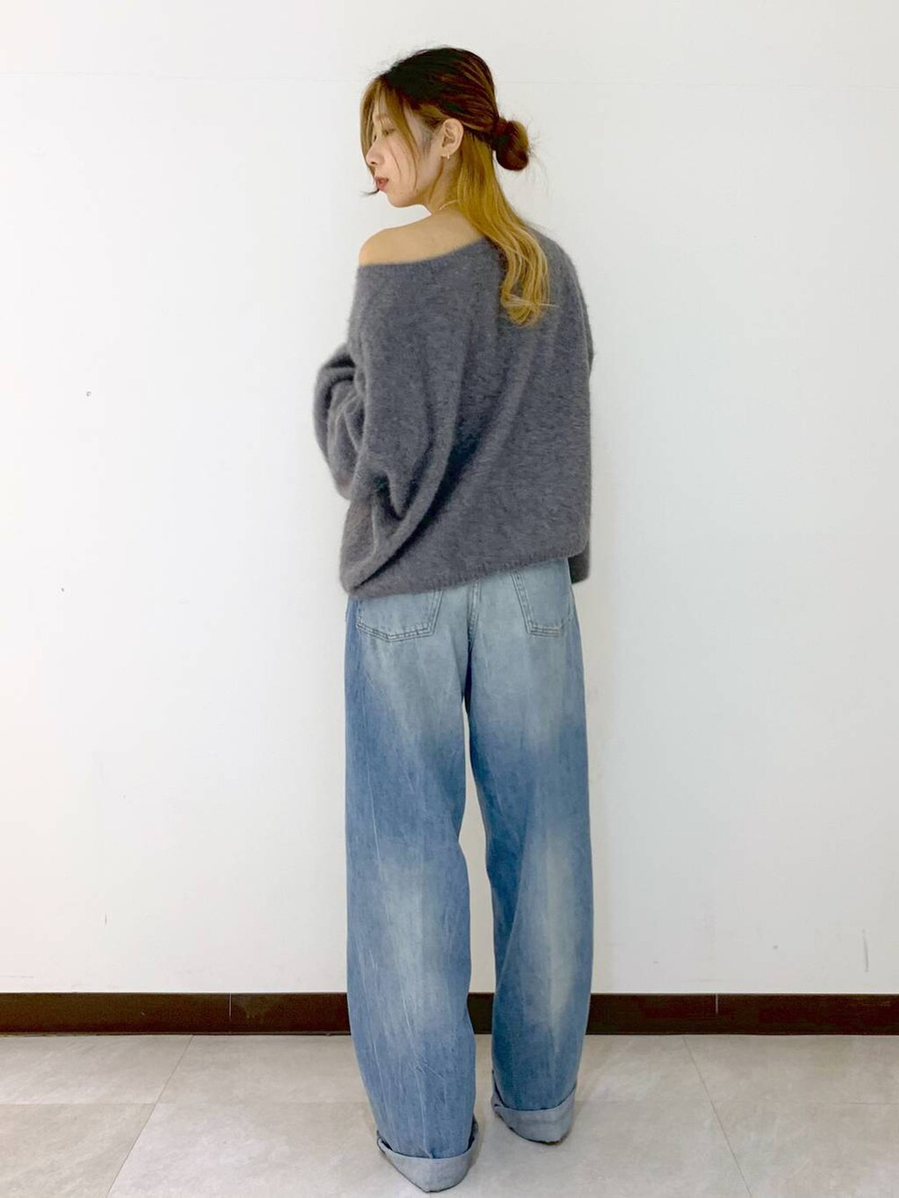 グレー系のニット/セーター、ブルー系のデニムパンツ、ゴールド系のネックレスを着用したレディースの冬コーディネートの4枚目の写真