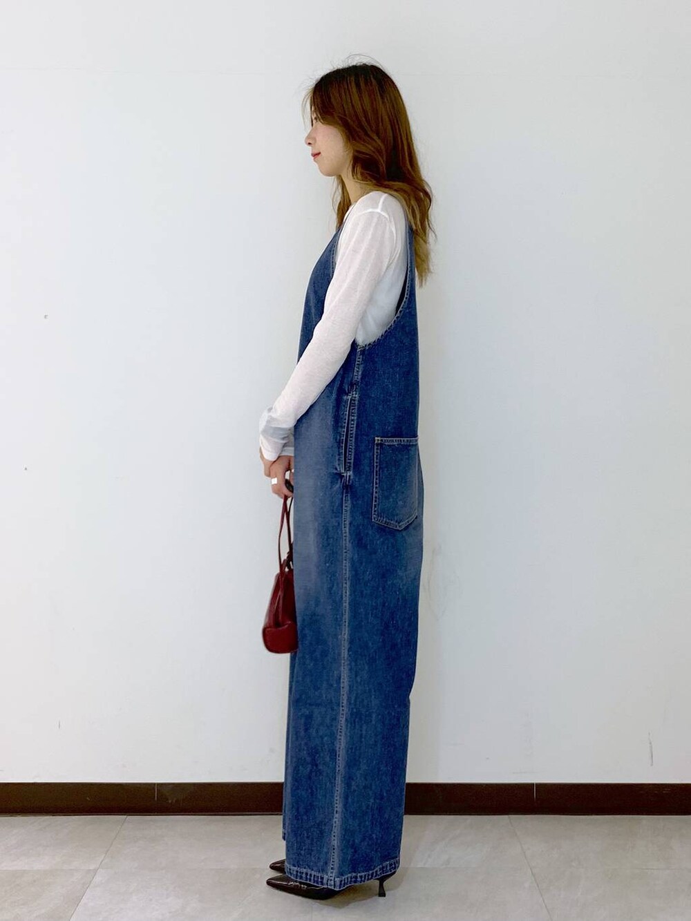 レッド系のショルダーバッグ、ホワイト系のTシャツ/カットソー、ブラウン系のソックス/靴下を着用したレディースの秋コーディネートの3枚目の写真