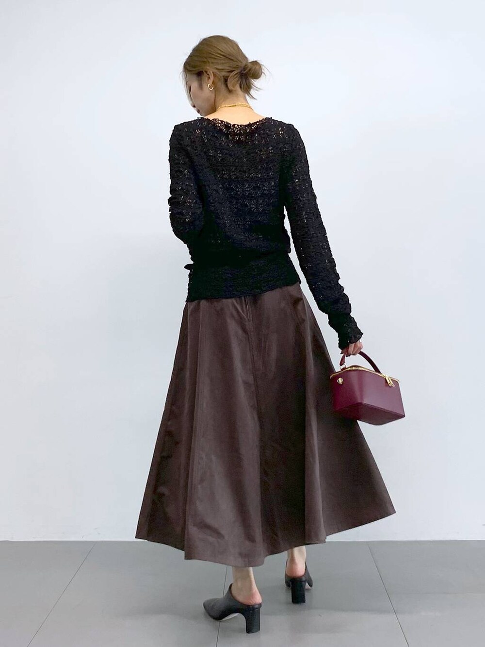 ブラック系のTシャツ/カットソー、ブラウン系のスカート、レッド系のハンドバッグを着用したレディースの冬コーディネートの4枚目の写真