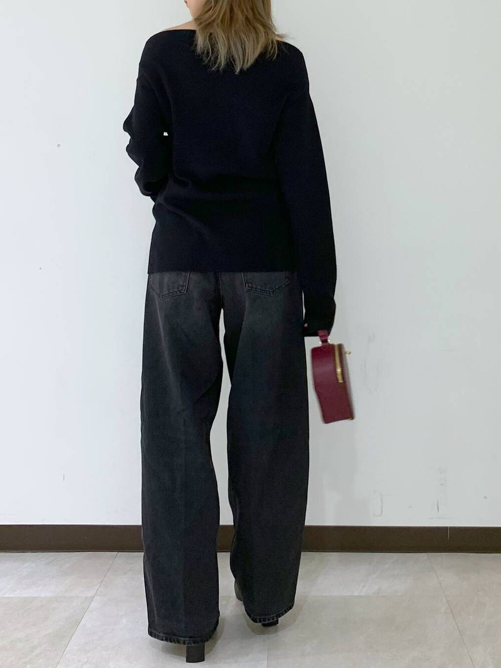 ブラック系のニット/セーター、ブラック系のデニムパンツ、レッド系のハンドバッグを着用したレディースの秋コーディネートの4枚目の写真