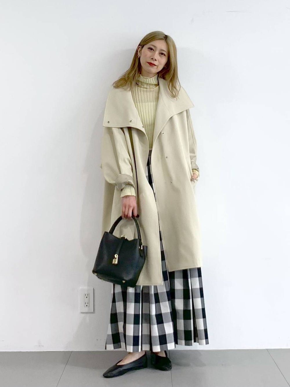 イエロー系のニット/セーター、ベージュ系のその他アウター、ブラック系のスカートを着用したレディースの冬コーディネートの6枚目の写真