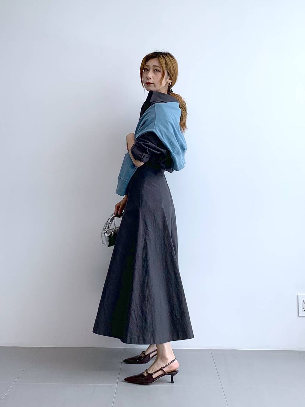 ブルー系のTシャツ/カットソー、シルバー系のショルダーバッグ、グレー系のスカートを着用したレディースの秋コーディネートの7枚目の写真