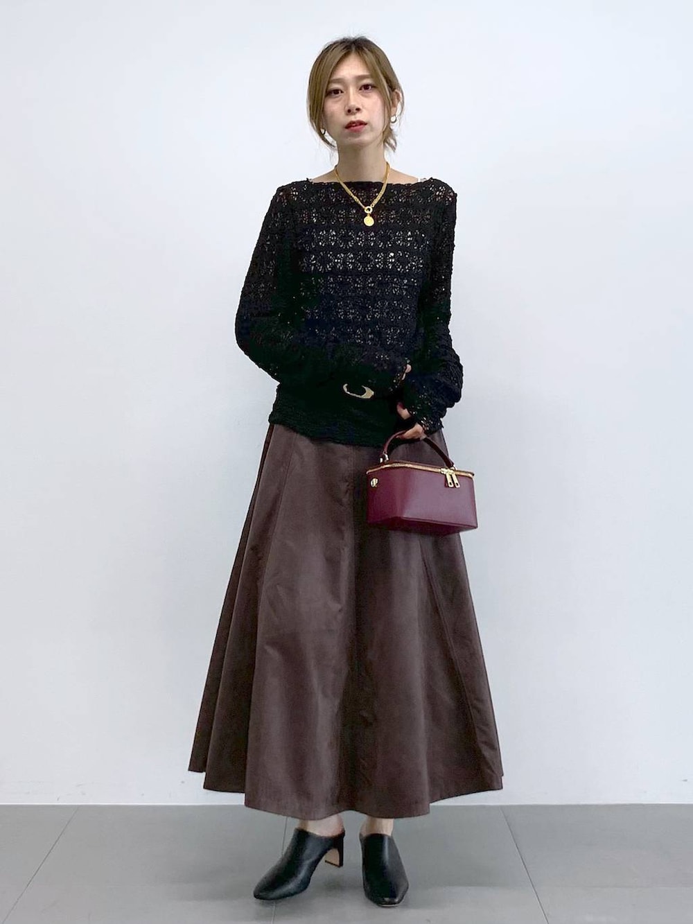 ブラック系のTシャツ/カットソー、ブラウン系のスカート、レッド系のハンドバッグを着用したレディースの冬コーディネートの2枚目の写真