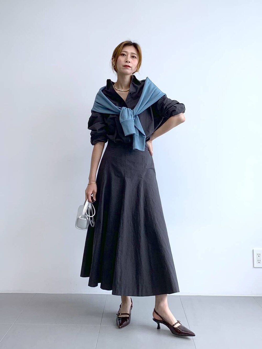 ブルー系のTシャツ/カットソー、シルバー系のショルダーバッグ、グレー系のスカートを着用したレディースの秋コーディネートの6枚目の写真