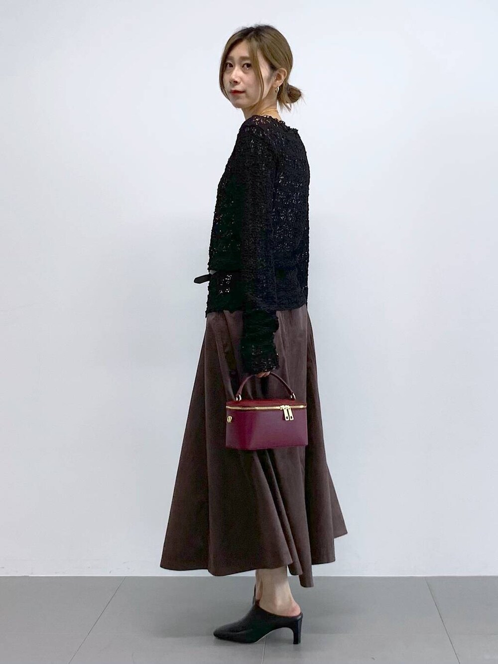 ブラック系のTシャツ/カットソー、ブラウン系のスカート、レッド系のハンドバッグを着用したレディースの冬コーディネートの3枚目の写真