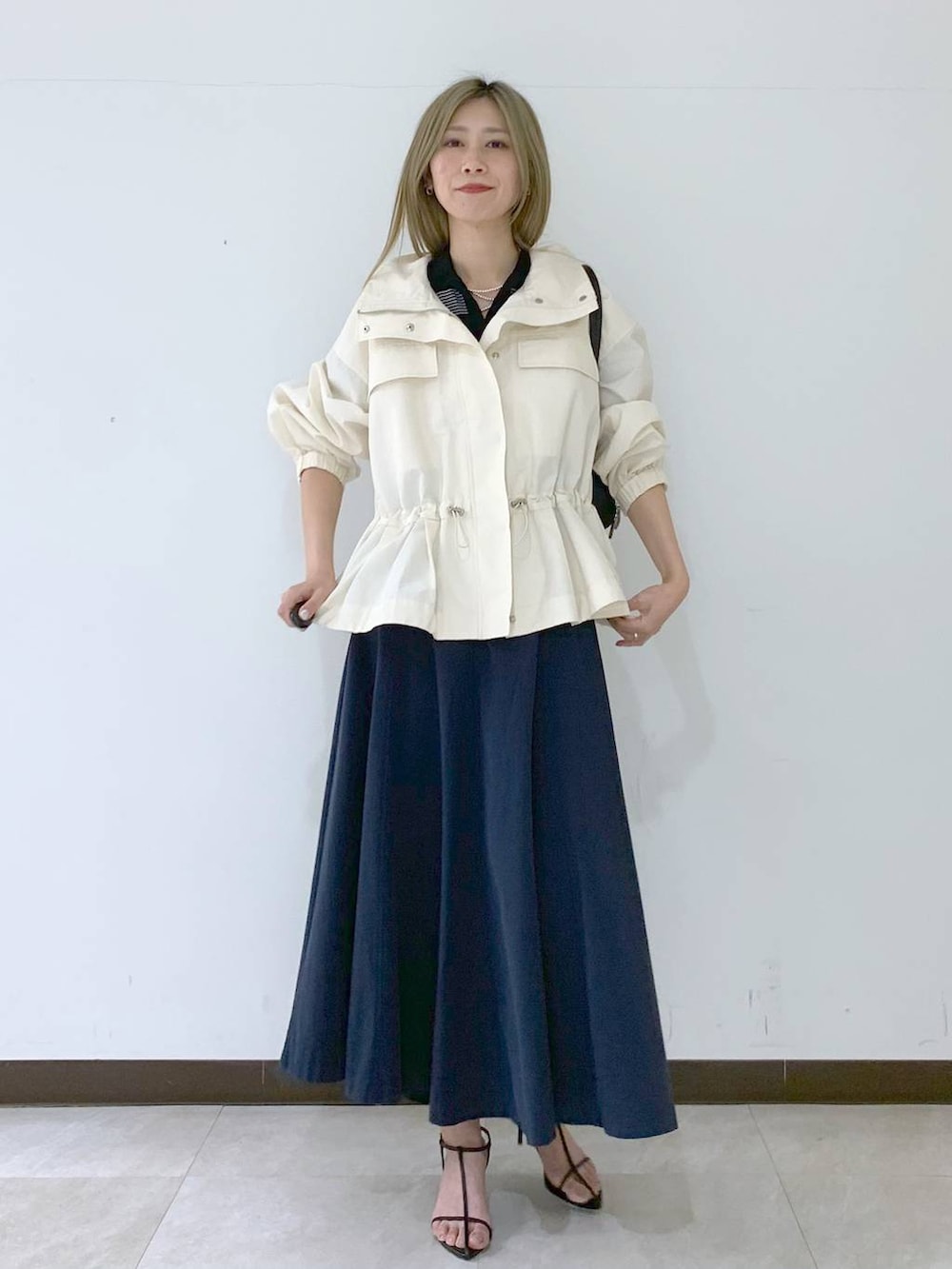 ブラック系のサンダル、ブラック系のハンドバッグ、ホワイト系のブルゾンを着用したレディースの春コーディネートの4枚目の写真