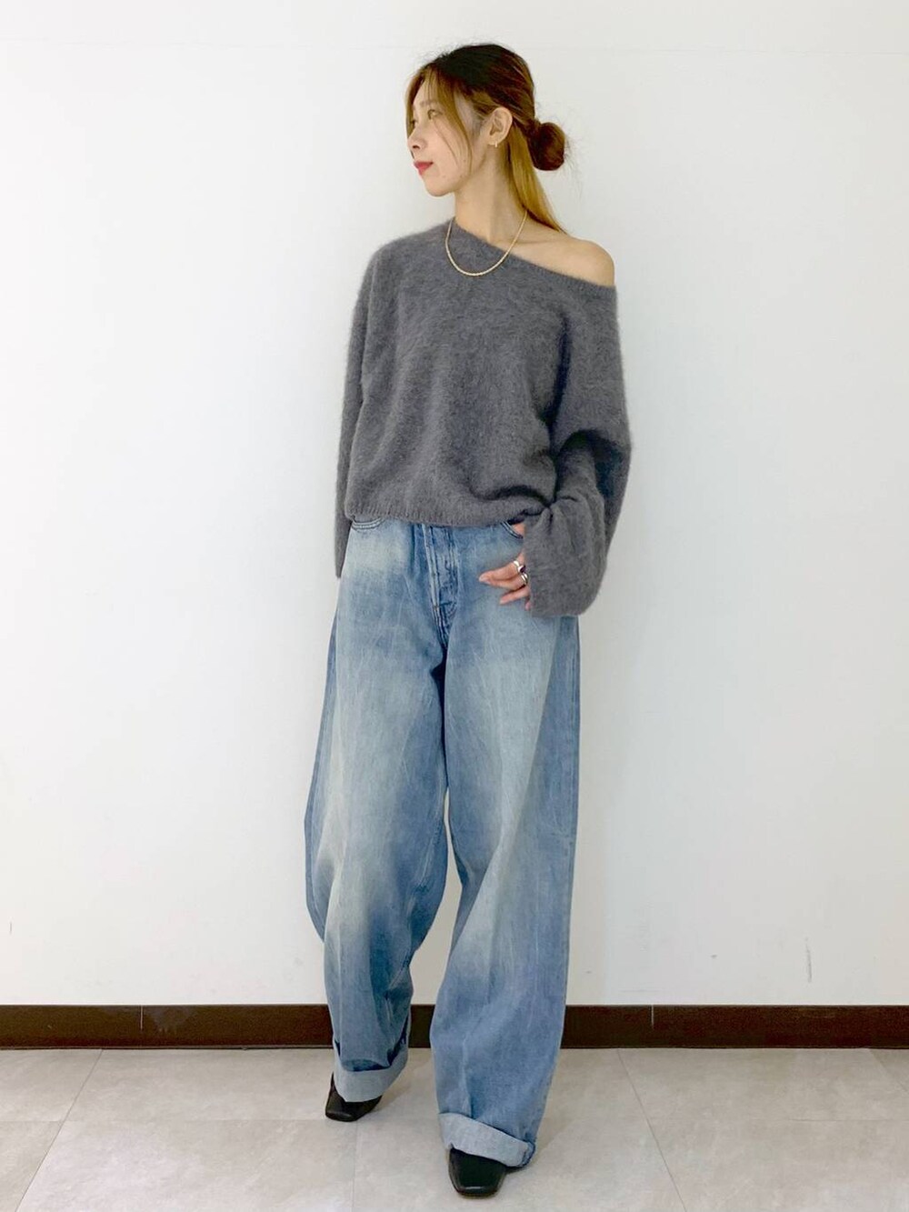 グレー系のニット/セーター、ブルー系のデニムパンツ、ゴールド系のネックレスを着用したレディースの冬コーディネートの2枚目の写真