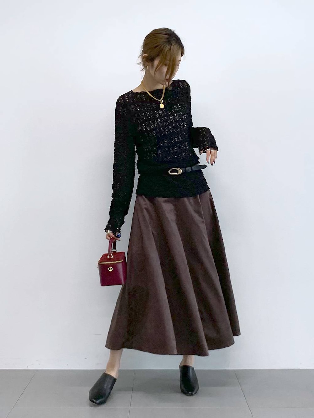 ブラック系のTシャツ/カットソー、ブラウン系のスカート、レッド系のハンドバッグを着用したレディースの冬コーディネートの5枚目の写真