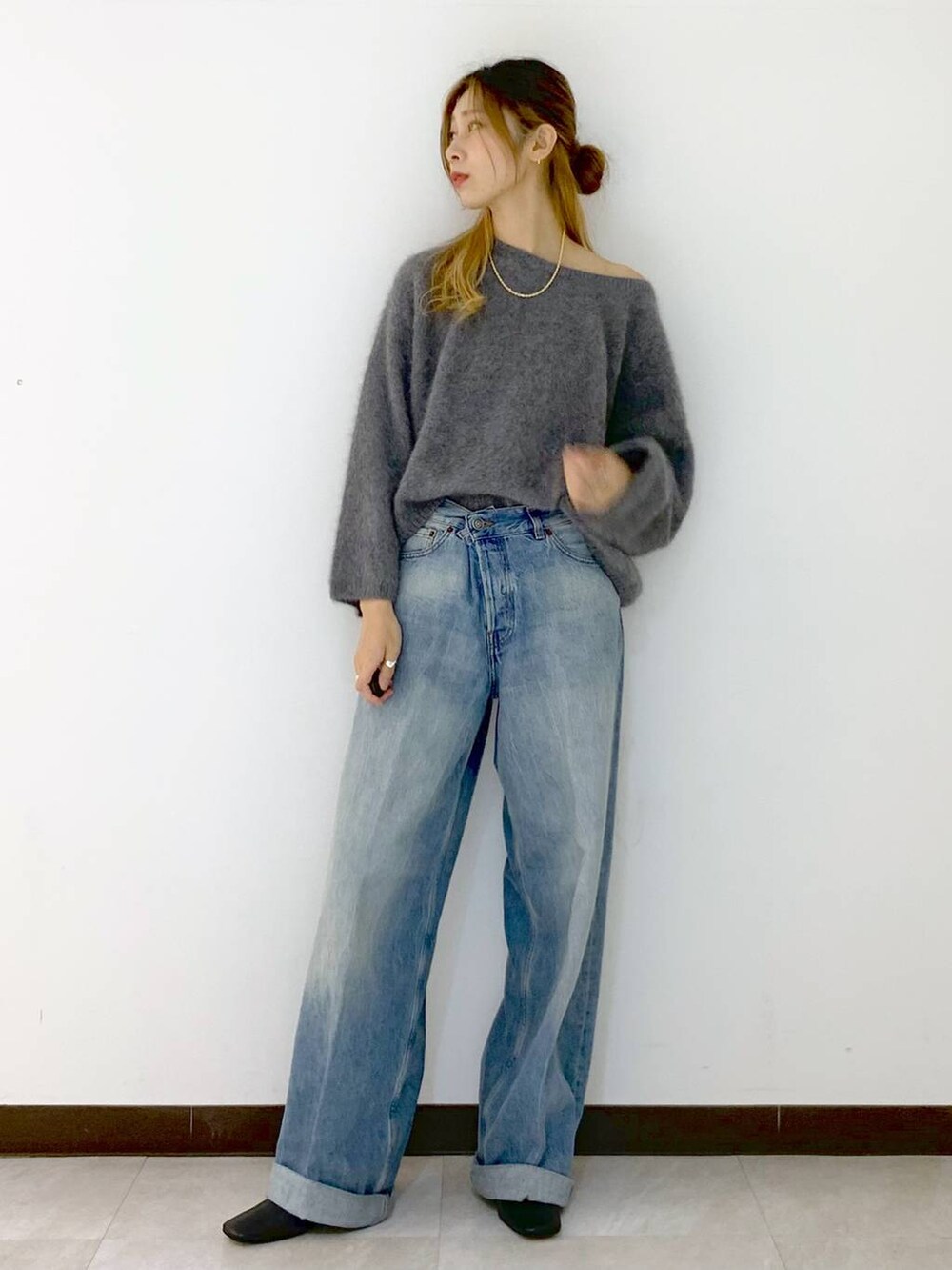 グレー系のニット/セーター、ブルー系のデニムパンツ、ゴールド系のネックレスを着用したレディースの冬コーディネートの5枚目の写真