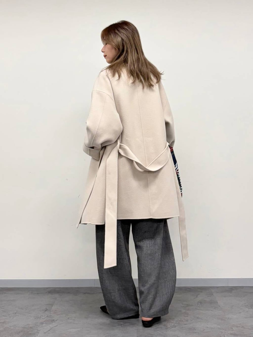 レッド系のトートバッグ、グレー系のその他パンツ、ベージュ系のステンカラーコートを着用したレディースの秋コーディネートの7枚目の写真