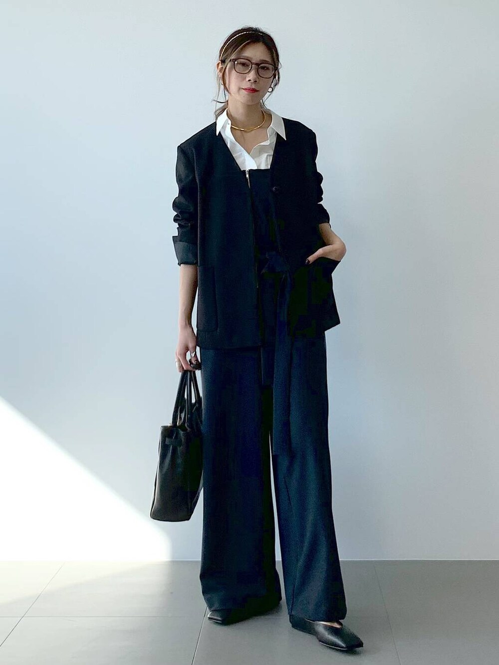 ブラック系のノーカラージャケット、ホワイト系のシャツ/ブラウス、ブラック系のつなぎ/オールインワンを着用したレディースの春コーディネートの2枚目の写真