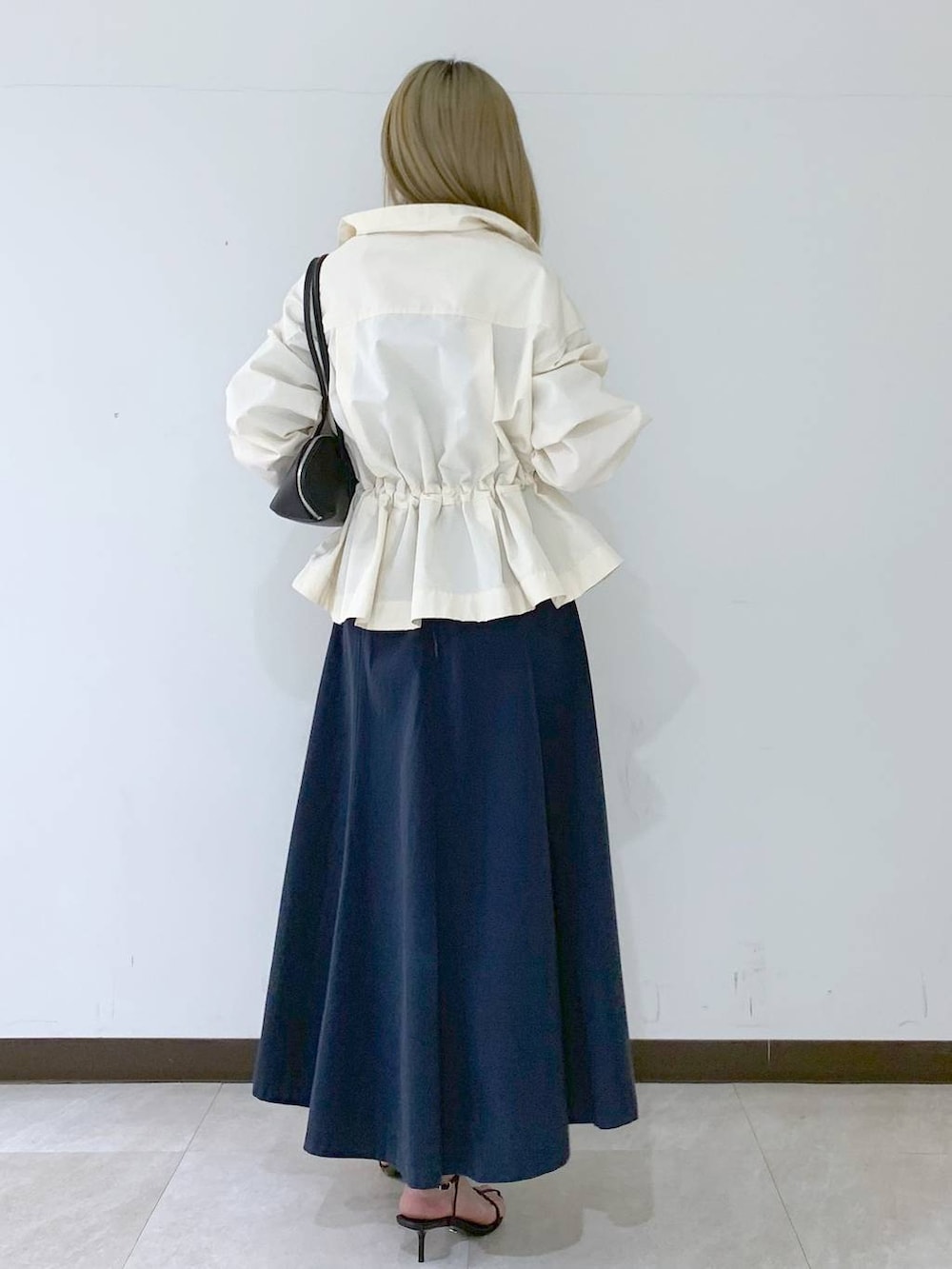 ブラック系のサンダル、ブラック系のハンドバッグ、ホワイト系のブルゾンを着用したレディースの春コーディネートの3枚目の写真