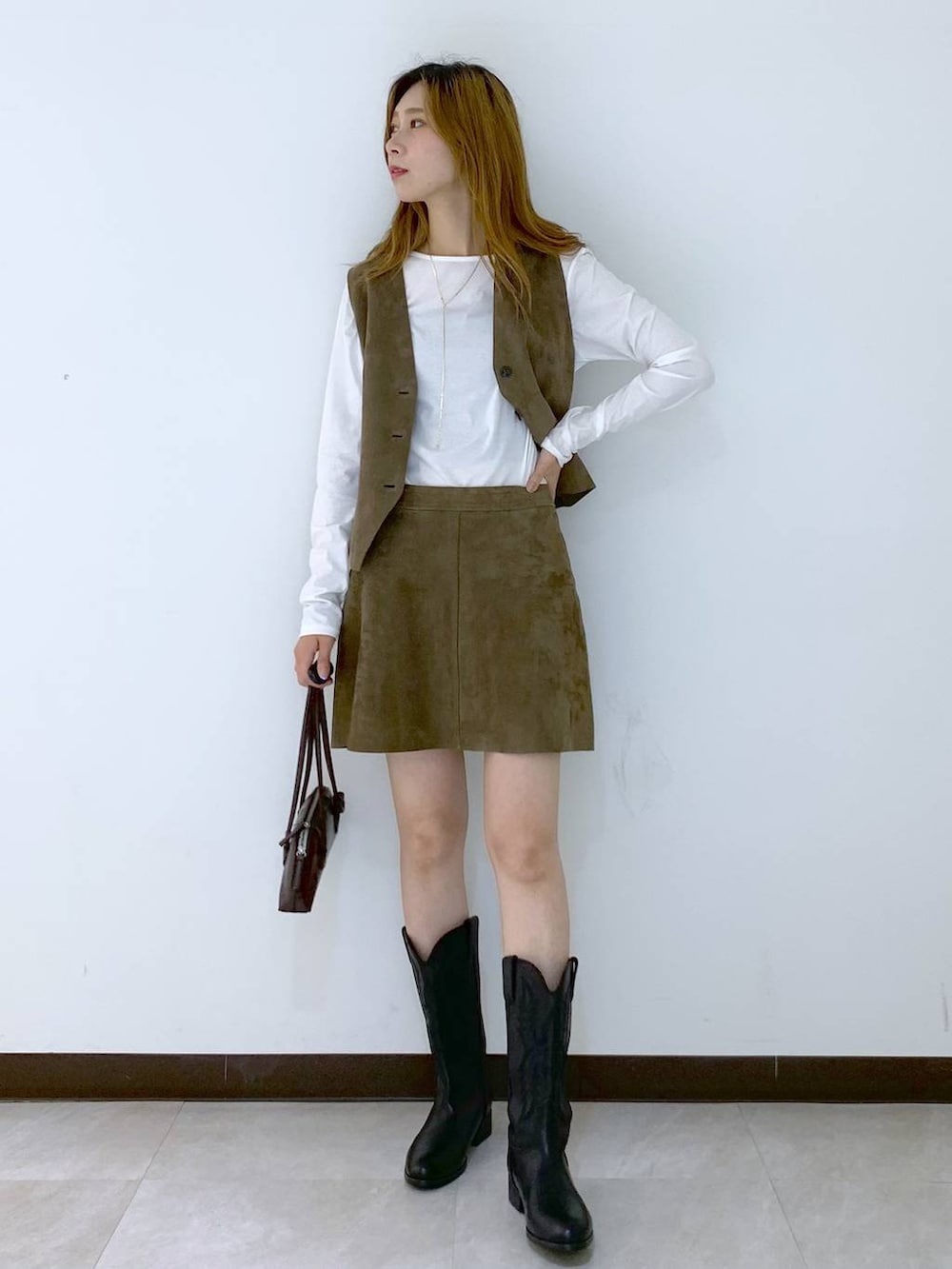 ホワイト系のTシャツ/カットソー、ブラウン系のショルダーバッグ、ベージュ系のベストを着用したレディースの秋コーディネートの6枚目の写真