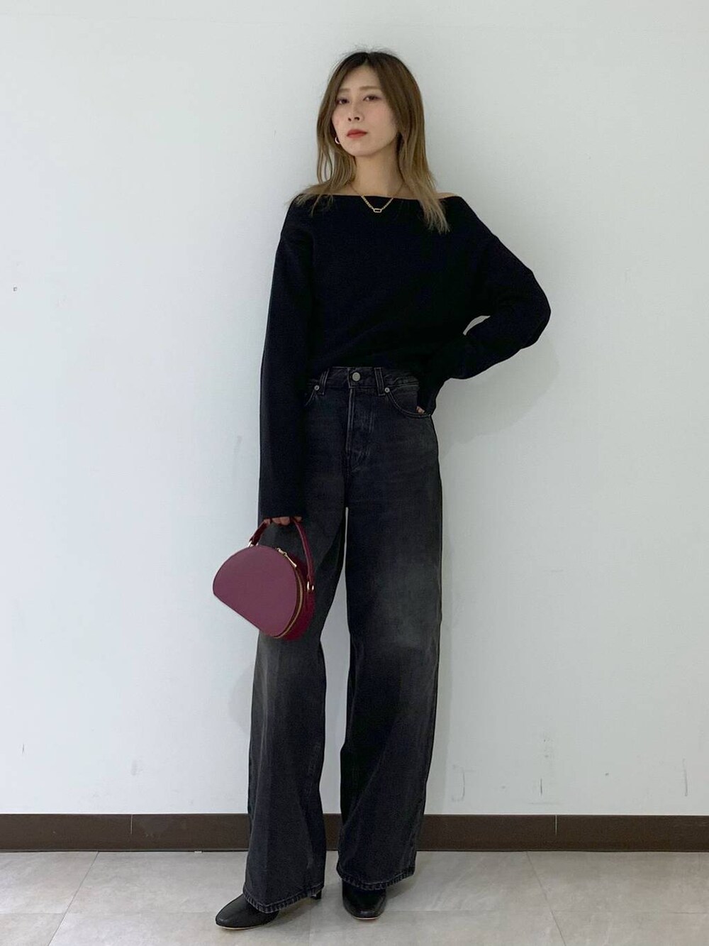 ブラック系のニット/セーター、ブラック系のデニムパンツ、レッド系のハンドバッグを着用したレディースの秋コーディネートの6枚目の写真