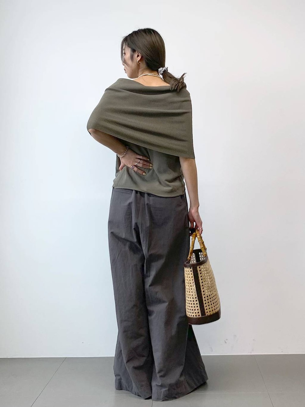 ブラック系のパンプス、ベージュ系のかごバッグ、グリーン系のニット/セーターを着用したレディースの春コーディネートの4枚目の写真