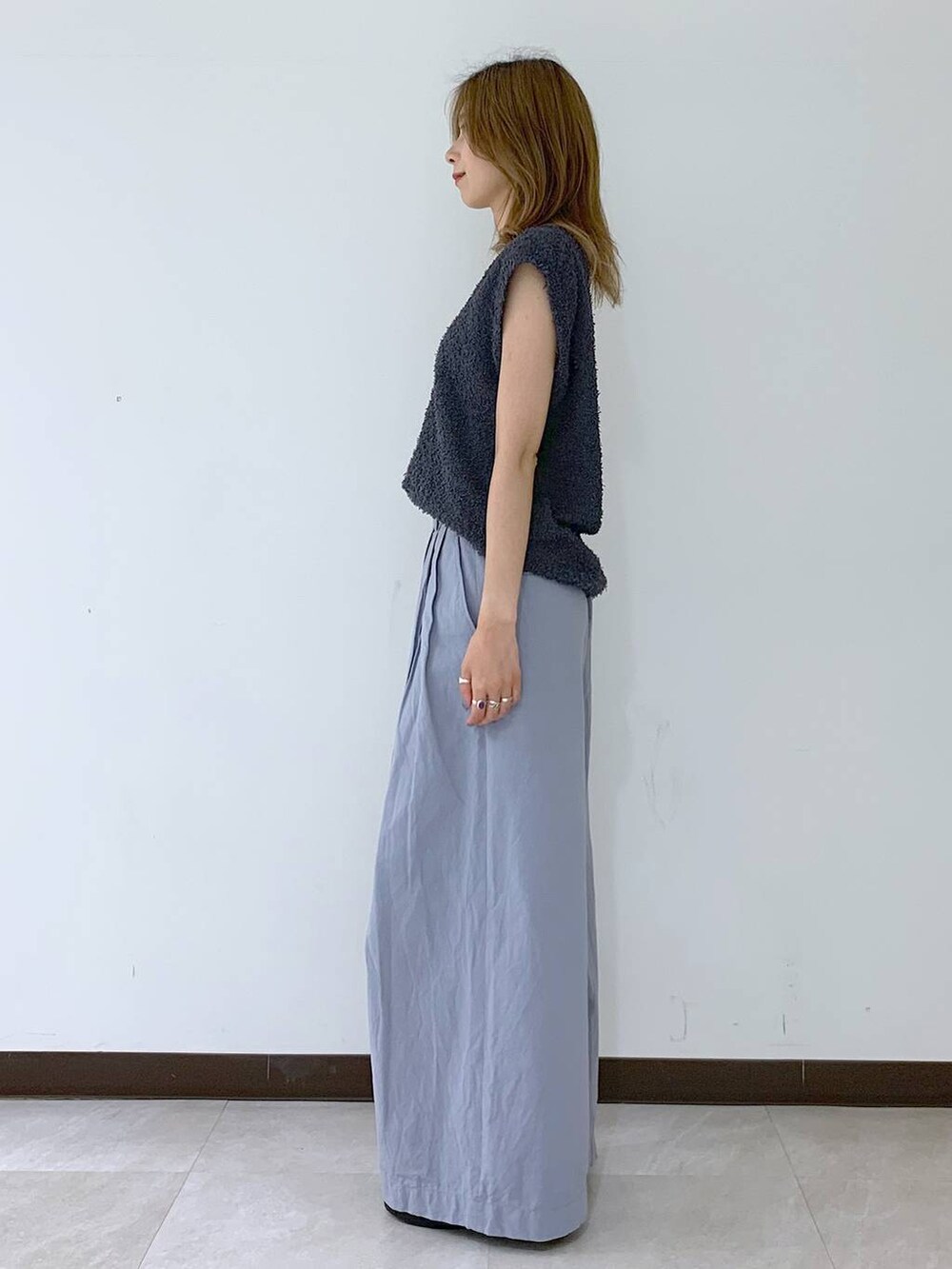 グレー系のニット/セーター、ブラック系のショルダーバッグ、ブラック系のスニーカーを着用したレディースの夏コーディネートの2枚目の写真