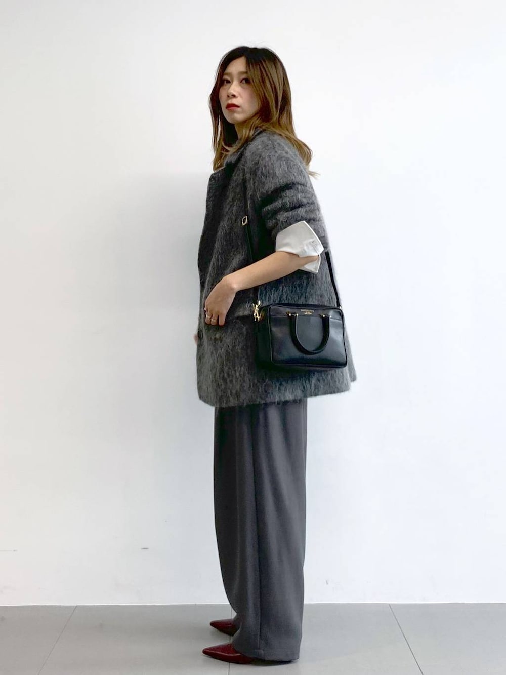 グレー系のその他パンツ、レッド系のブーツ、ブラック系のボストンバッグを着用したレディースの冬コーディネートの2枚目の写真