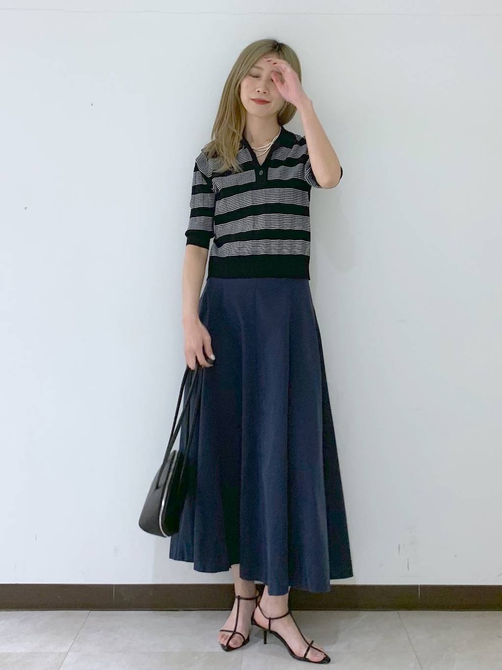 ブラック系のサンダル、ブラック系のハンドバッグ、ブラック系のポロシャツを着用したレディースの春コーディネートの5枚目の写真