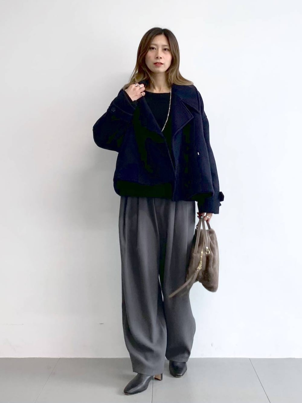 グレー系のその他パンツ、ブラック系のブーツ、ブラウン系のハンドバッグを着用したレディースの冬コーディネートの2枚目の写真