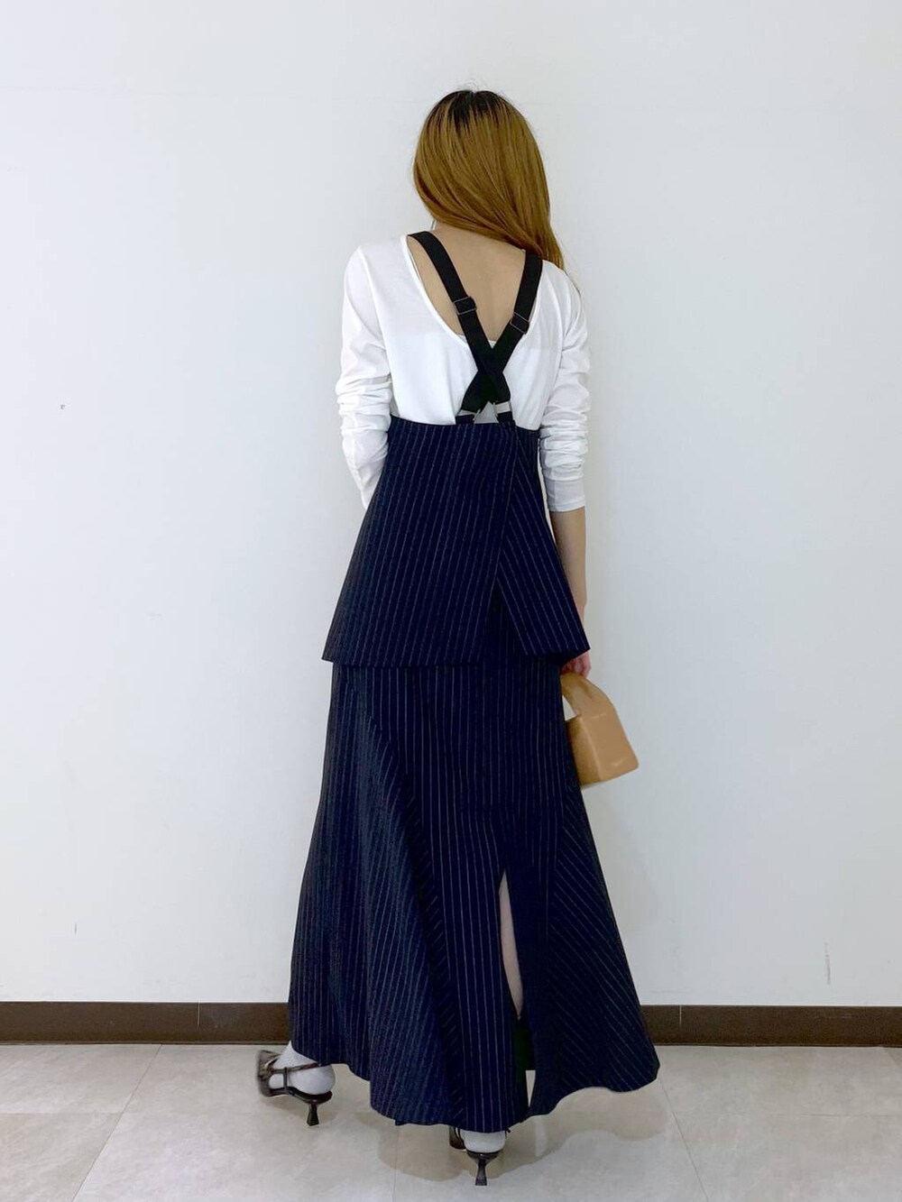 ブルー系のベスト、ブルー系のスカート、ホワイト系のTシャツ/カットソーを着用したレディースの秋コーディネートの3枚目の写真