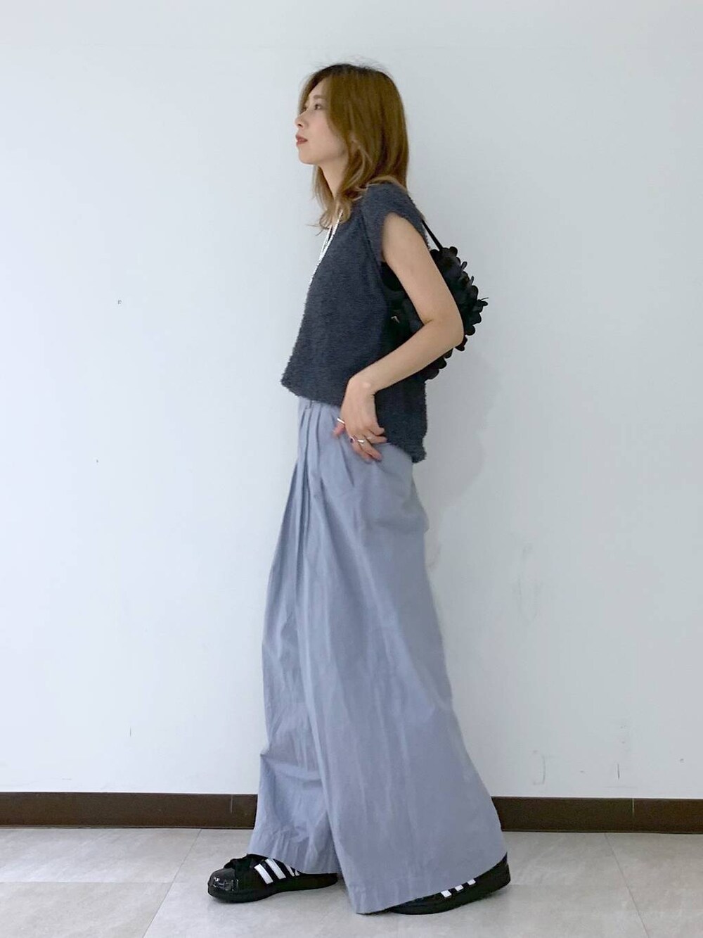 グレー系のニット/セーター、ブラック系のショルダーバッグ、ブラック系のスニーカーを着用したレディースの夏コーディネートの6枚目の写真