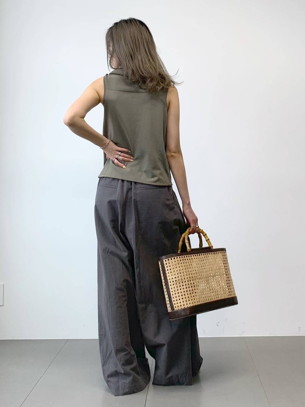 ブラック系のパンプス、ベージュ系のかごバッグ、グリーン系のニット/セーターを着用したレディースの春コーディネートの8枚目の写真