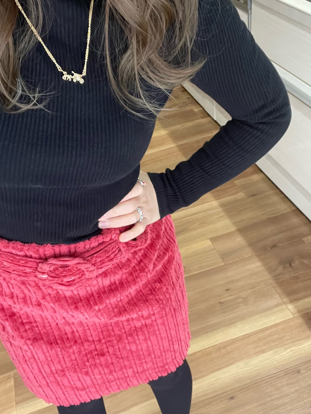 ピンク系のスカート、ブラック系のダウンジャケット/コート、ゴールド系のネックレスを着用したレディースの冬コーディネートの2枚目の写真