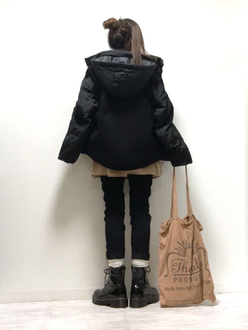 ブラック系のベスト、ブラック系のダウンジャケット/コート、ベージュ系のトートバッグを着用したレディースの秋コーディネートの3枚目の写真