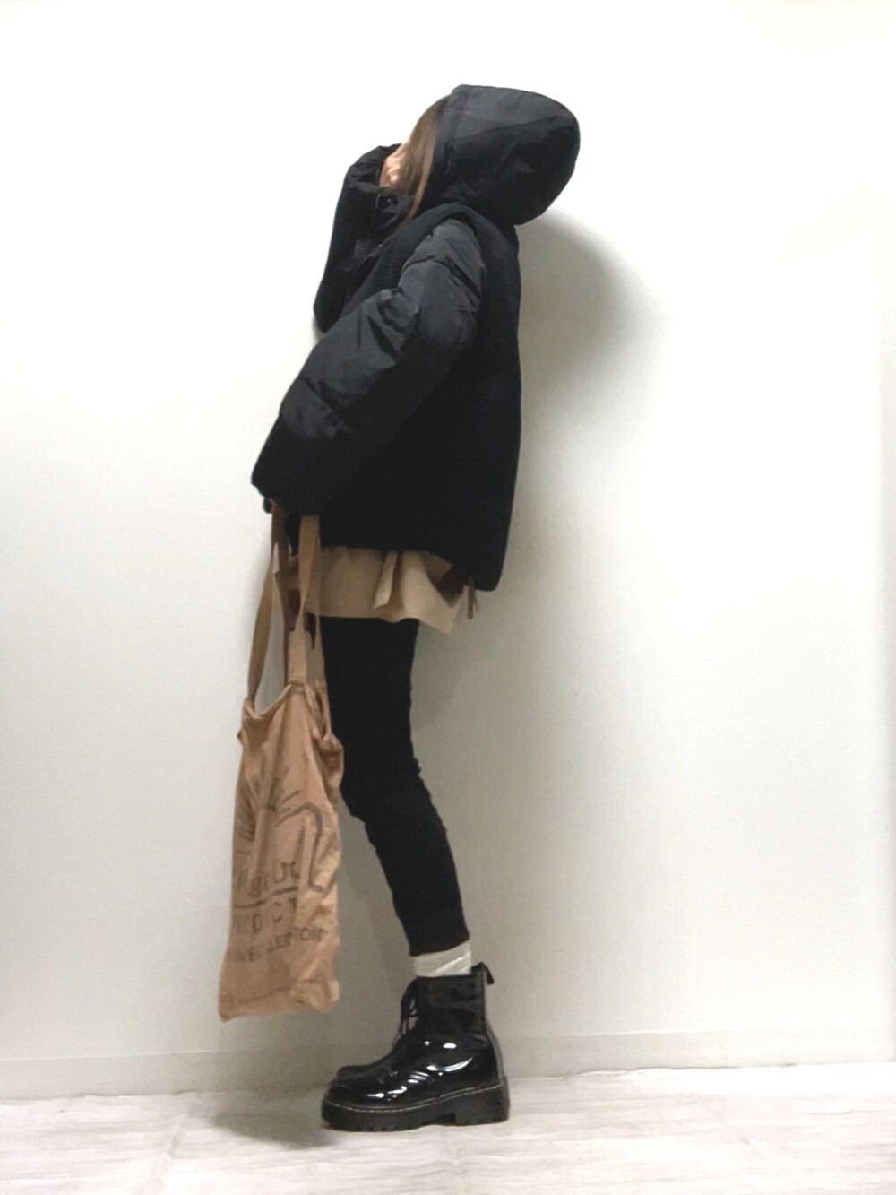 ブラック系のベスト、ブラック系のダウンジャケット/コート、ベージュ系のトートバッグを着用したレディースの秋コーディネートの2枚目の写真