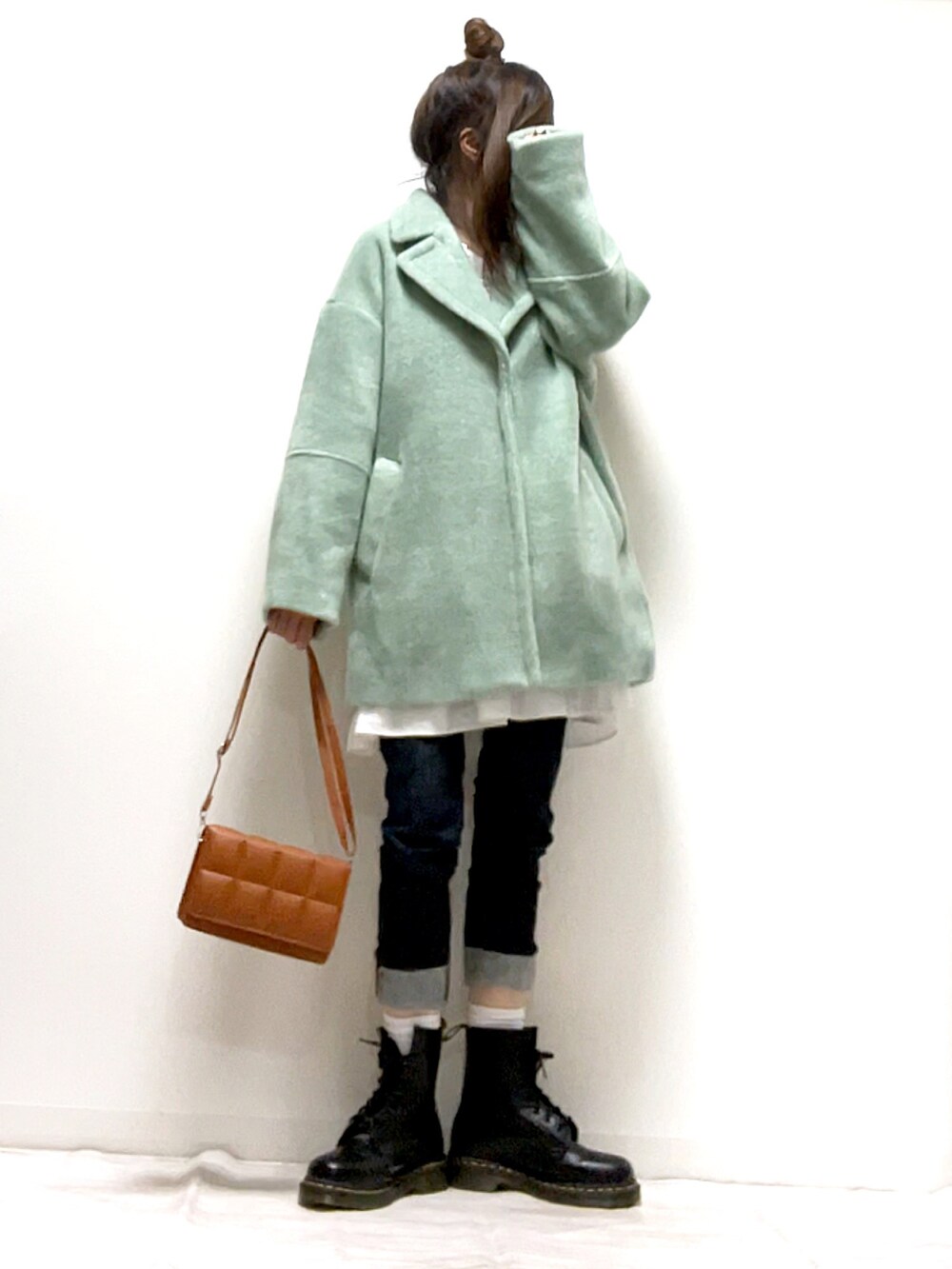 グリーン系のチェスターコート、ブラウン系のクラッチバッグ、ブラック系のブーツを着用したレディースの秋コーディネートの3枚目の写真