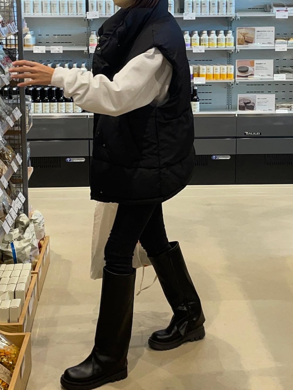 ブラック系のデニムパンツ、ブラック系のブーツ、ホワイト系のスウェットを着用したレディースの秋コーディネートの3枚目の写真