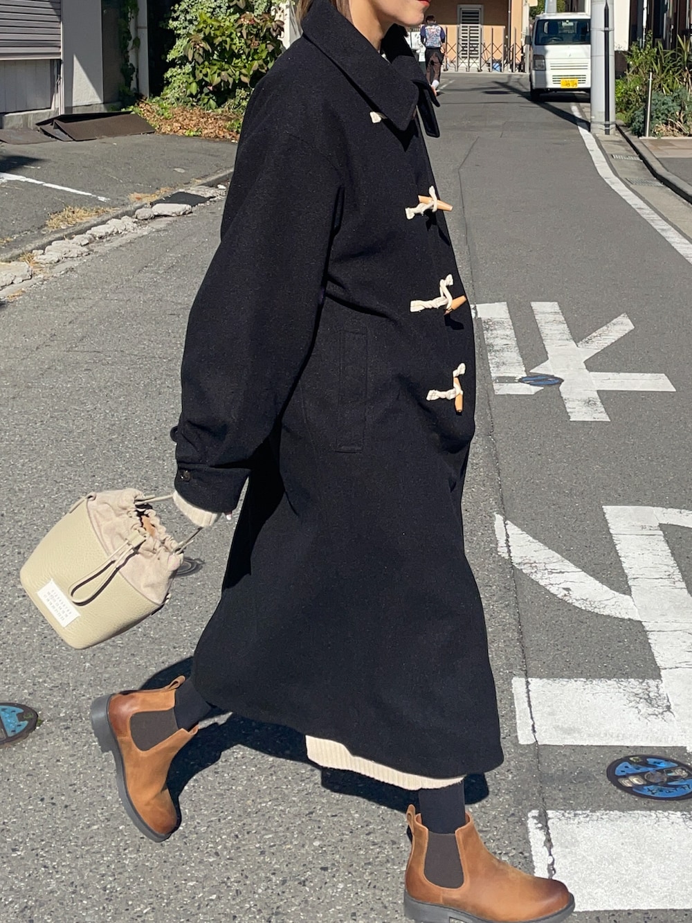 ベージュ系のショルダーバッグ、ブラック系のダッフルコート、ブラウン系のブーツを着用したレディースの秋コーディネートの2枚目の写真