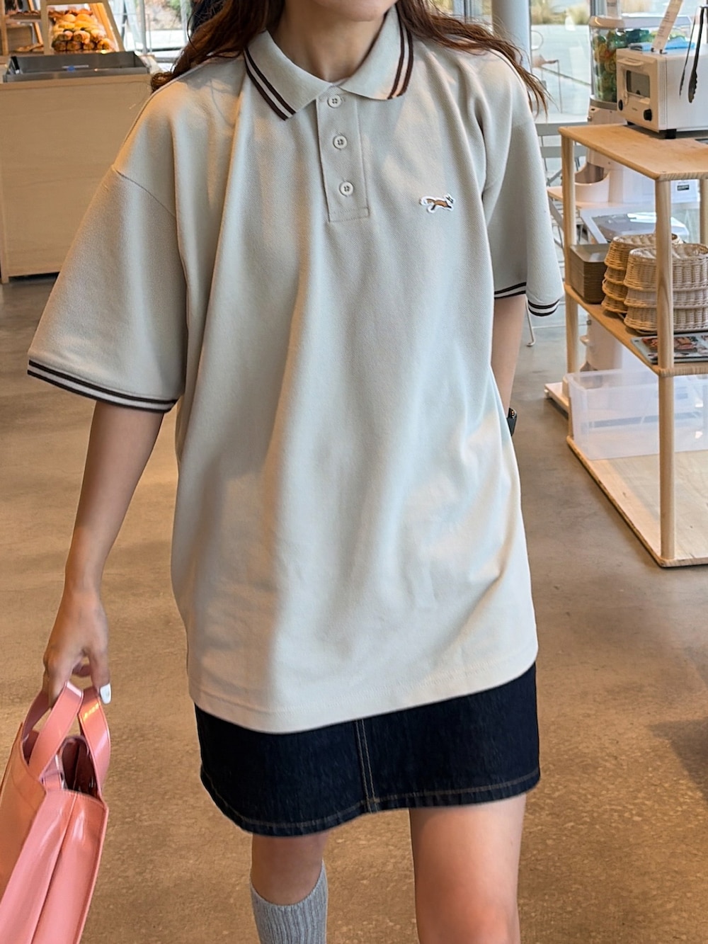 ホワイト系のポロシャツを着用したレディースの春コーディネートの2枚目の写真