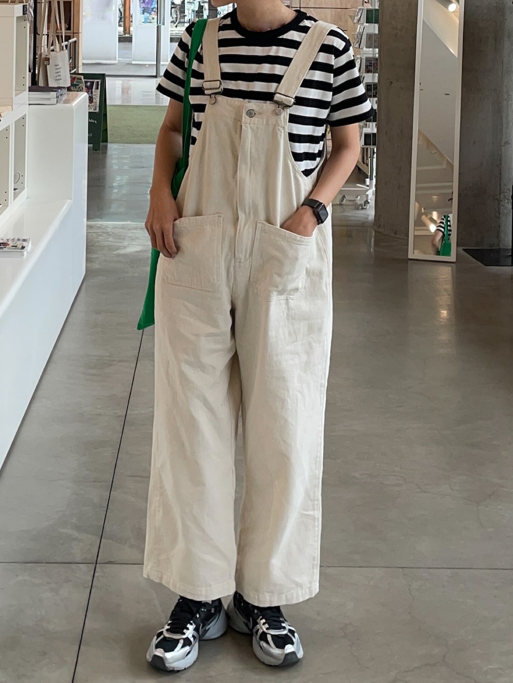 ブラック系のスニーカー、グリーン系のトートバッグ、ホワイト系のTシャツ/カットソーを着用したレディースの春コーディネートの2枚目の写真