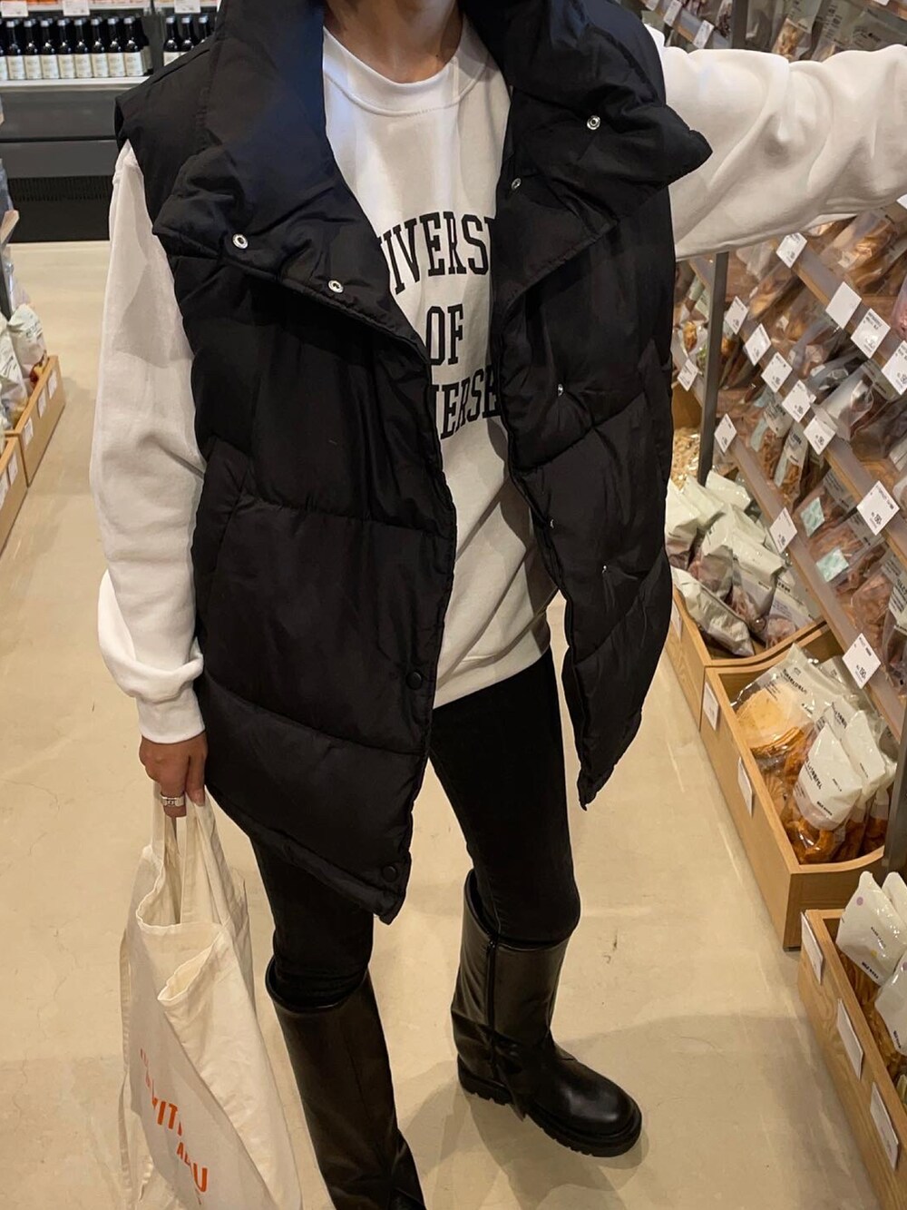 ブラック系のデニムパンツ、ブラック系のブーツ、ホワイト系のスウェットを着用したレディースの秋コーディネートの2枚目の写真