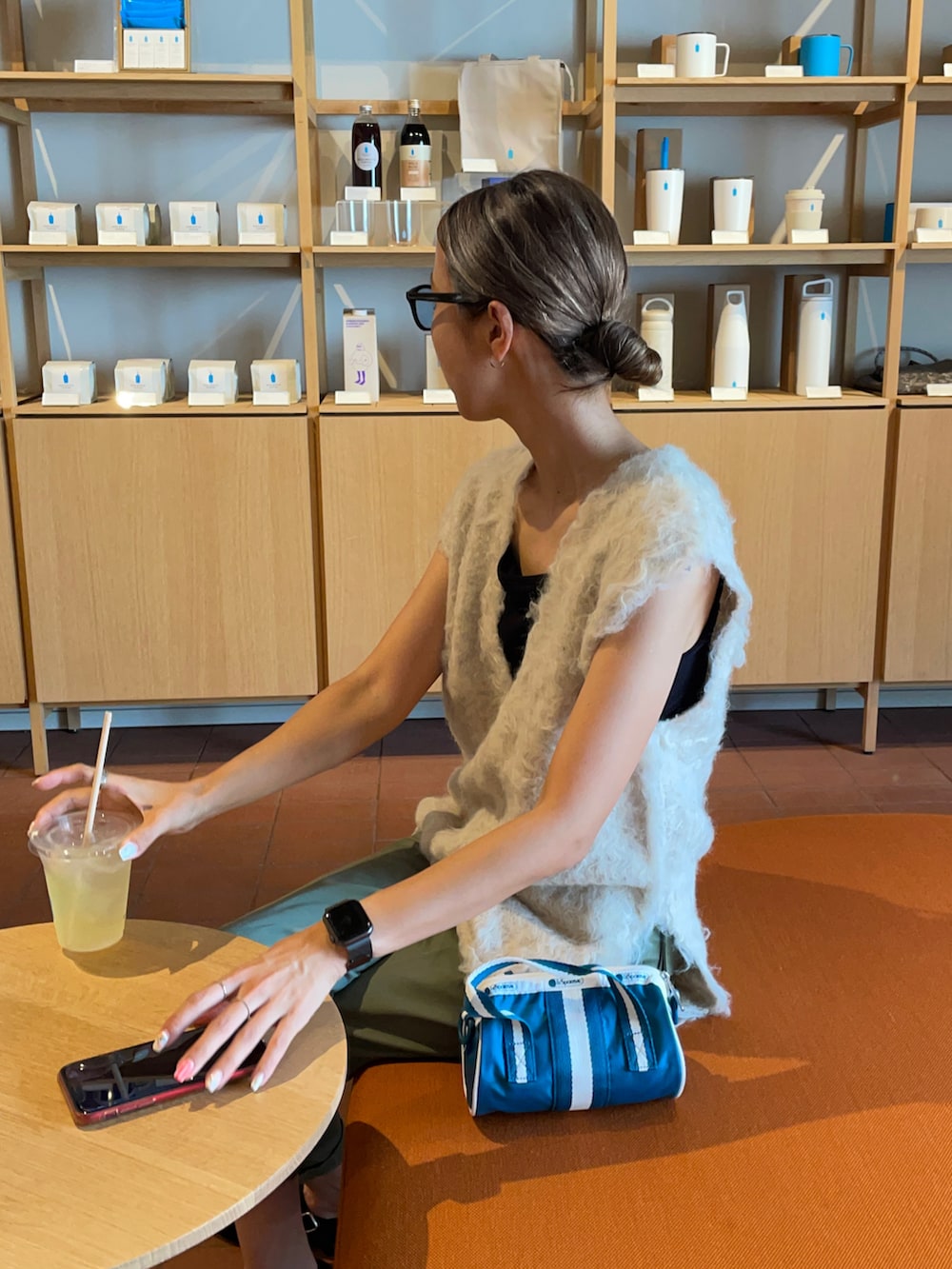 グリーン系のチノパンツ、ホワイト系のベスト、ブルー系のショルダーバッグを着用したレディースの秋コーディネートの3枚目の写真