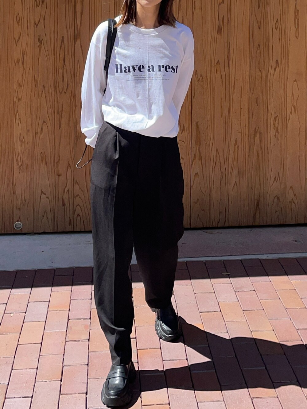 ブラック系のバッグ、ブラック系のスニーカー、ホワイト系のTシャツ/カットソーを着用したレディースの夏コーディネートの3枚目の写真